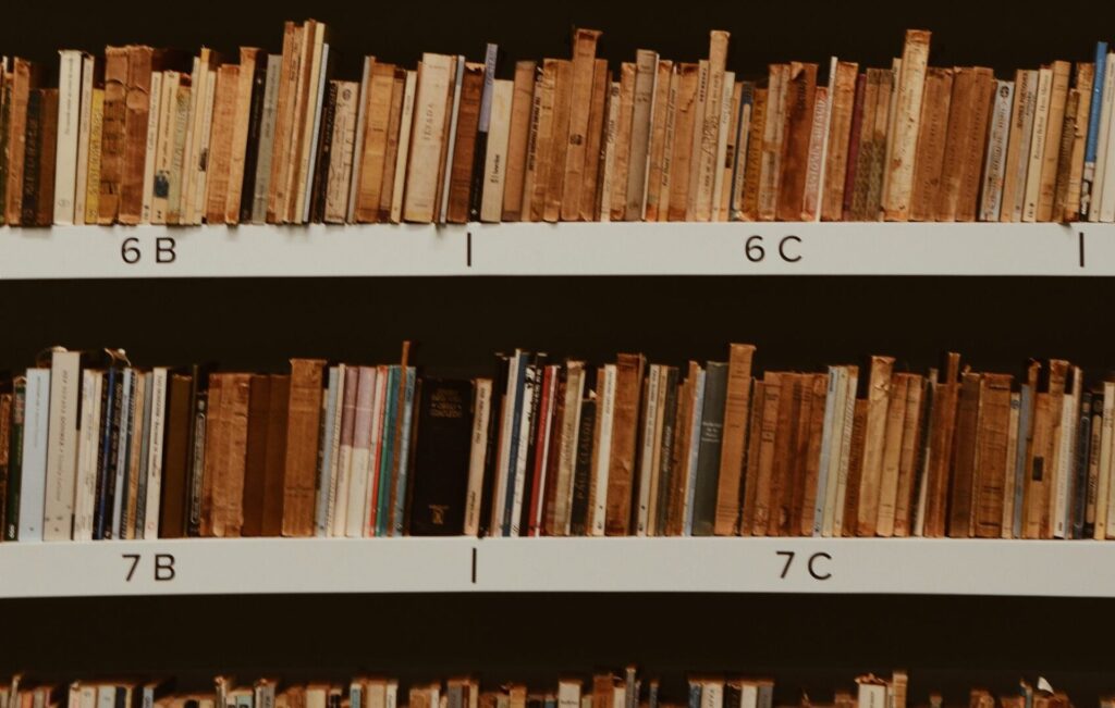 Photo of a metal bookshelf filled with old and worn books.