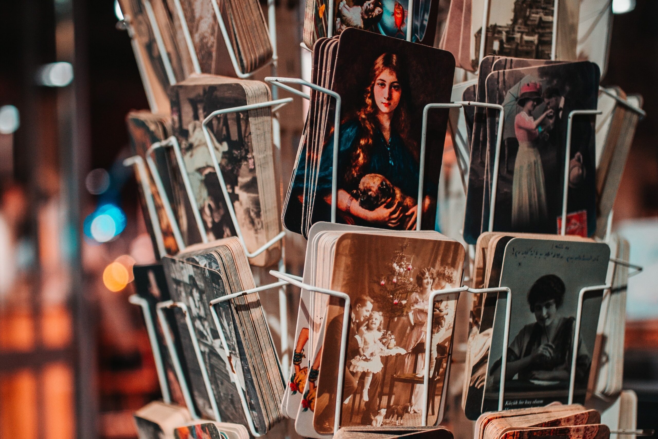 Photograph of a wire postcard rack with a variety of old-fashioned postcards.